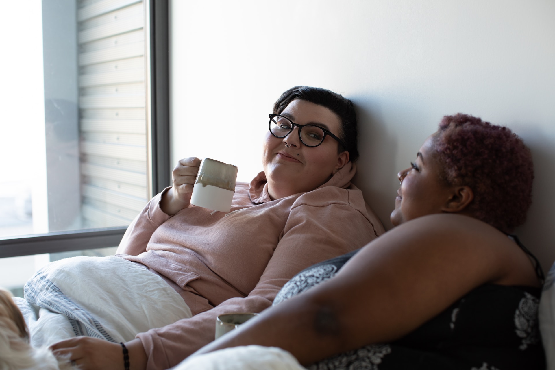 Two women snuggle up with coffee.