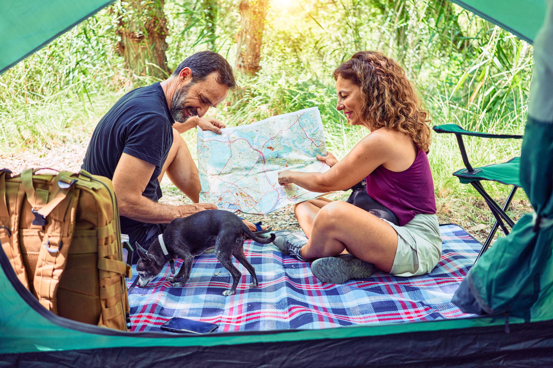 A couple sits in a tent, reading a map together.