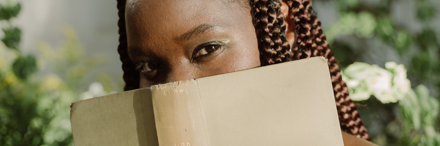 A person hiding their face behind a book.